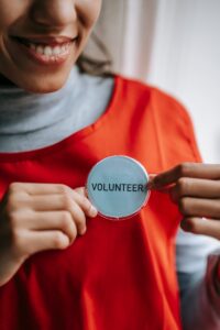 Gros plan d'un bénévole souriant tenant un badge dans un cadre lumineux.