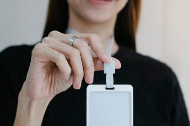Portrait d'une femme joyeuse tenant un badge d'identification vierge, parfait pour la promotion d'une entreprise ou d'un événement.