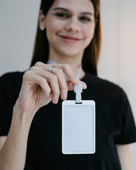 Portrait d'une femme joyeuse tenant un badge d'identification vierge, parfait pour la promotion d'une entreprise ou d'un événement.