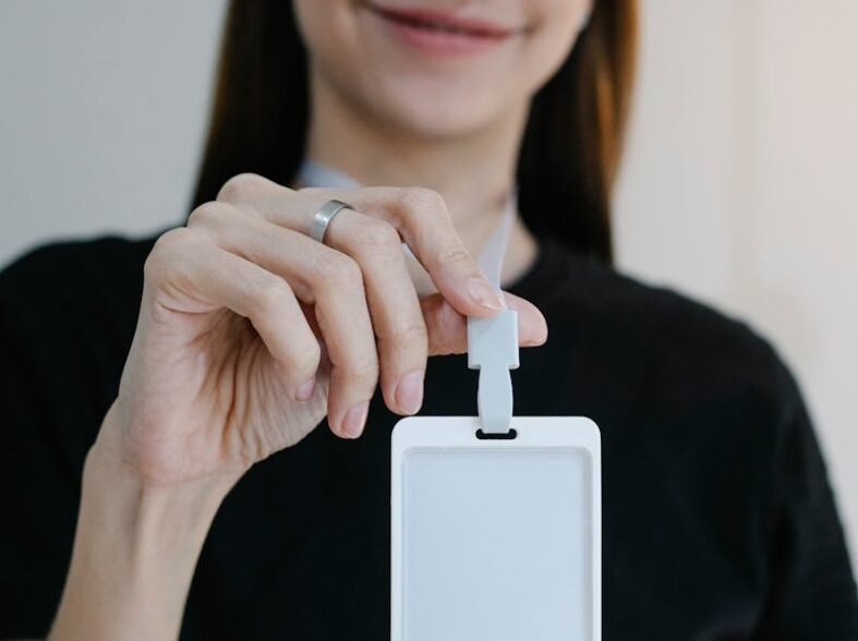 Portrait d'une femme joyeuse tenant un badge d'identification vierge, parfait pour la promotion d'une entreprise ou d'un événement.