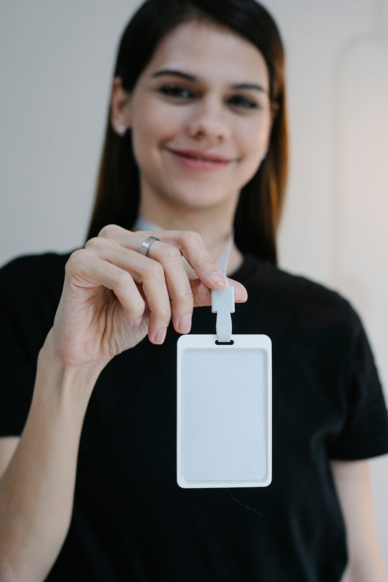 Portrait d'une femme joyeuse tenant un badge d'identification vierge, parfait pour la promotion d'une entreprise ou d'un événement.